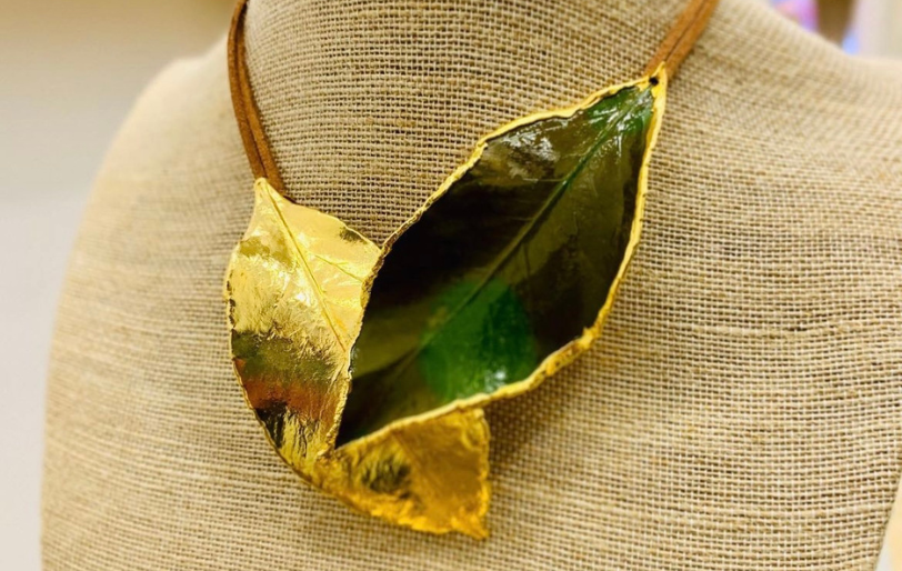 Un colgante de paparajotes de oro con un lado del paparajote de color verde.